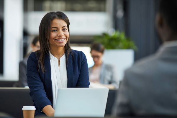 woman at a laptop sitting across from someone smiling